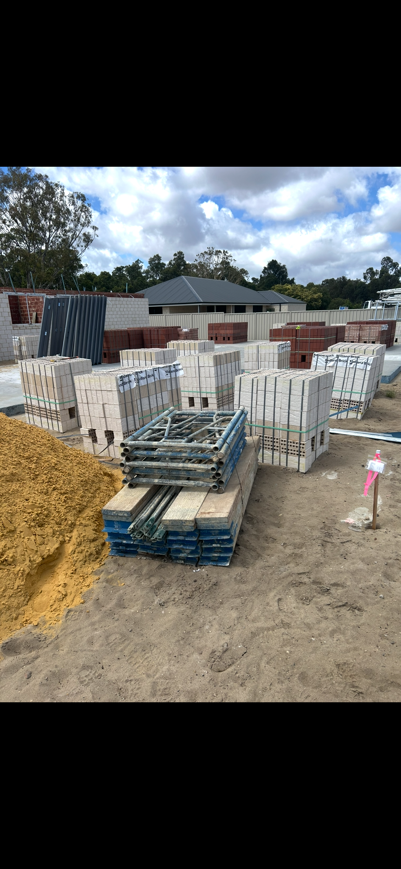 Containment Group brickies kit stacked beside Midland Brick pallets at a Perth single-storey build